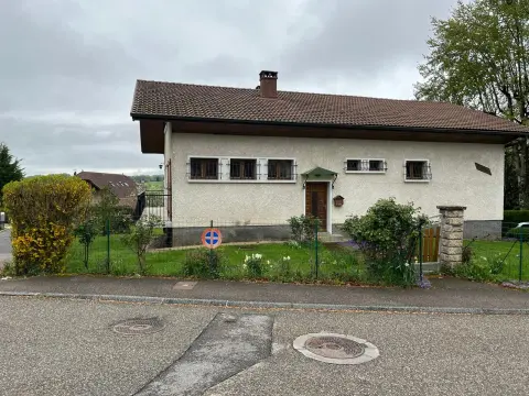 La façade côté rue, l'entrée abritée d'un auvent vert et le jardin clos par une clôture basse.