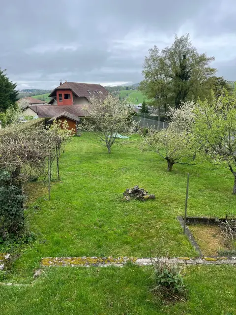 Le terrain de 1 200 m², dégagé et plat au fond, avec vue sur les collines et les maisons du village.