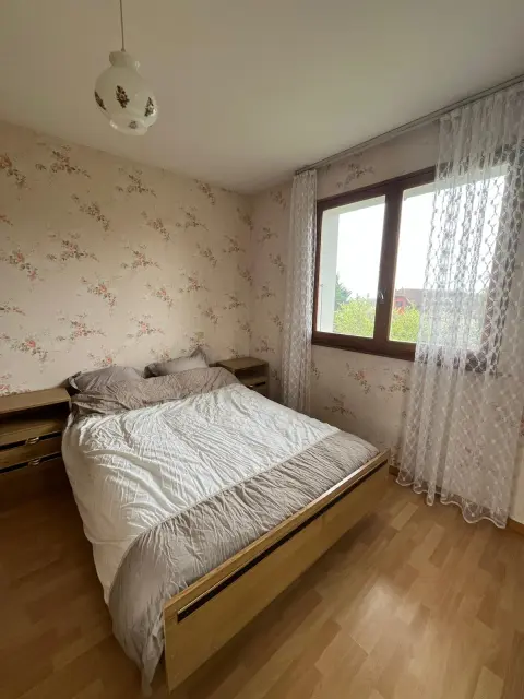 Une chambre avec lit double de 140 × 190, sa fenêtre et son parquet clair.
