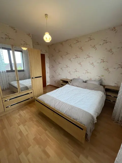Une chambre avec lit double de 140 × 190, armoire et grande fenêtre.