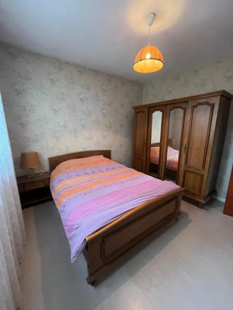Une chambre double avec son lit fait à l'arrivée et son miroir en pied.